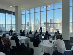 A speaker addresses a group of individuals, the skyline of downtown los angeles can be seen in the background.