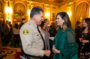 CEO Nella McOsker and Sheriff Luna celebrate at the Central City Association’s holiday party, socializing in a festive indoor setting with warm lighting and seasonal décor.